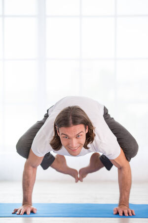 Young man practicing yoga, doing crow poseの写真素材