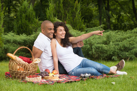 Portrait of a smiling girl pointing at something while having picnicの写真素材
