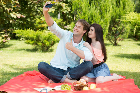 Happy romantic couple taking pictures at picnicの写真素材
