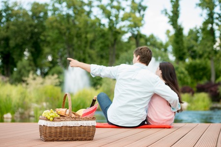 Happy romantic couple enjoying picnic in a park near lakeの写真素材