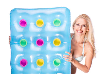 Smiling young woman in swimsuit holding colored air-bad, isolated on whiteの写真素材