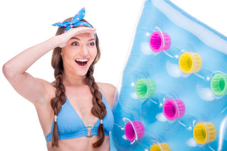 Smiling young woman in swimsuit surprising and holding colored air-bad, isolated on whiteの写真素材