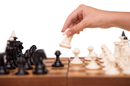 Close-up of woman hand moving white chess horse in a chess game, isolated on whiteの写真素材