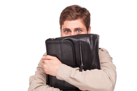 Young handsome scared businessman holding black briefcase, isolated on white backgroundの写真素材