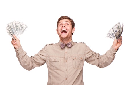 Cheerful young man holding soft money and happily smiling, isolated on whiteの写真素材