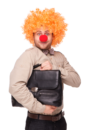 Funny picture of young businessman wearing clown wig and nose and holding briefcase, isolated on whiteの写真素材