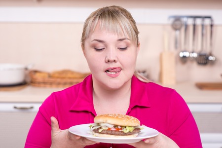 Overweight pretty woman desiring to eat big unhealthy hamburgerの写真素材