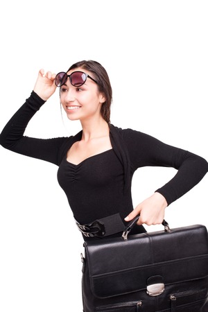 Smiling young beautiful business woman with sunglasses standing isolated on white background and holding briefcaseの写真素材