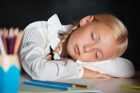 Little tired school girl has fallen asleep during lessonの写真素材