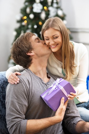 Young beautiful woman giving Christmas present to her boyfriendの写真素材
