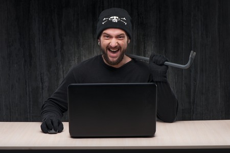 Computer hacker at work with a laptop holding breaker. Computer hacker conceptの写真素材