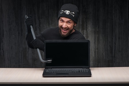 Computer hacker at work with a laptop holding breaker. Computer hacker conceptの写真素材