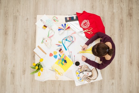 Top view of table full of creative things with young woman drawing. Fashion designer conceptの写真素材