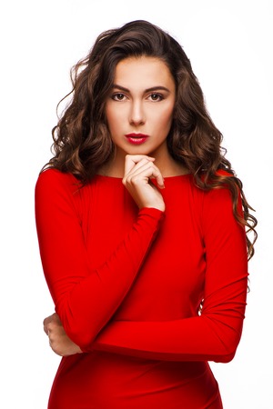 Gorgeous woman with curly hair in red dress looking severely at camera, isolated on white backgroundの写真素材