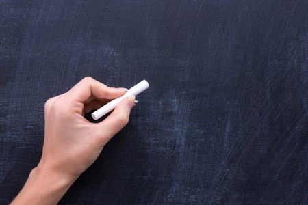 Mans hand holding a piece of white chalkの写真素材