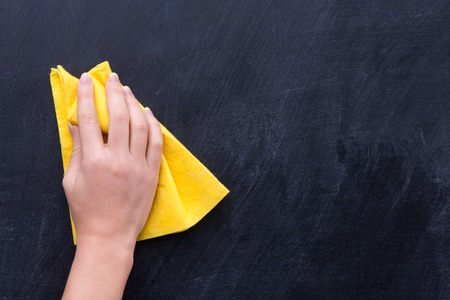 Hand with yellow rag erasing something from blackboard