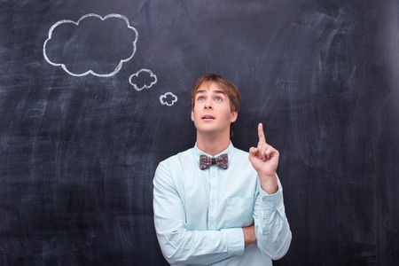 Man standing in front of blackboard and shoving finger upの写真素材
