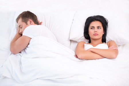 Top view photo of young couple lying in bed under white blanket after a quarrel. Offended and sleepless womanの写真素材