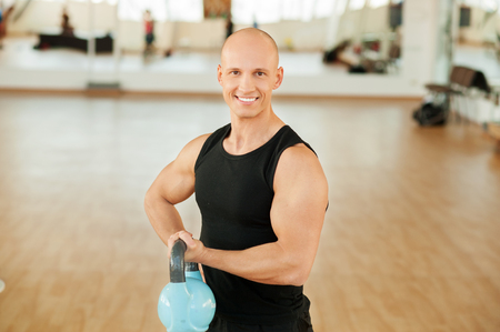 Male bodybuilding doing a work out lifting kettlebellの写真素材