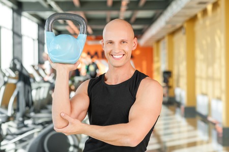 Male bodybuilding doing a work out lifting kettlebell one handの写真素材