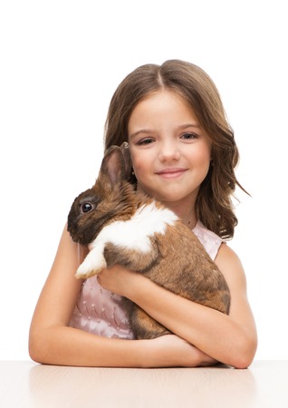 Beautiful little girl holding cute brown bunny, isolated on white backgroundの写真素材