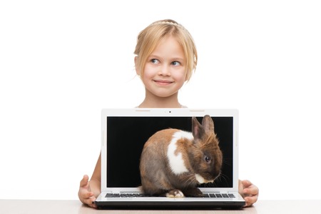 Beautiful girl looking aside and holding laptop where little bunny is sitting, isolated on white backgroundの写真素材