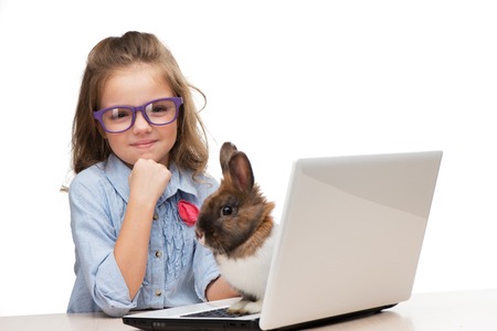 Cute girl in glasses with laptop and little bunny on it, isolated on white backgroundの写真素材