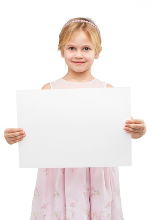 Little girl wearing pink dress, standing isolated on white background and holding white blank paperの写真素材