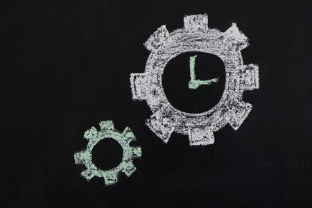 Photo of gears and clock painted with chalk on dark chalkboardの写真素材