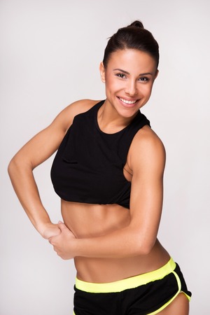 Smiling mixed race sporty woman looking at camera, isolated on white backgroundの写真素材