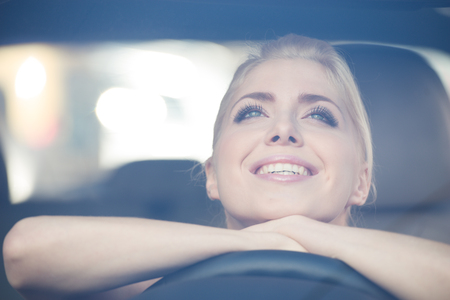 Happy beautiful young woman leaned on the steering wheel of the carの写真素材