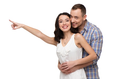Woman points at something. Both lovers looking at camera. Isolated on white backgroundの写真素材