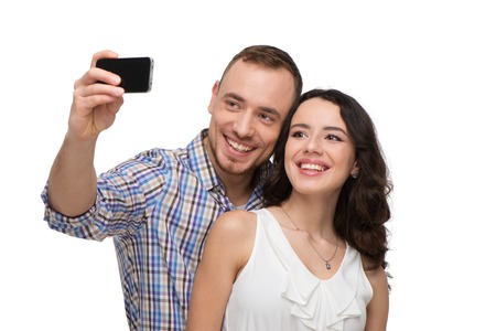 Boyfriend and girlfriend making selfie on phone. They look happy. Isolated on white backgroundの写真素材