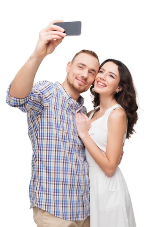 Boyfriend and girlfriend making selfie on phone. They look happy. Isolated on white backgroundの写真素材