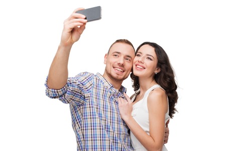 Boyfriend and girlfriend making selfie on phone. They look happy. Isolated on white backgroundの写真素材