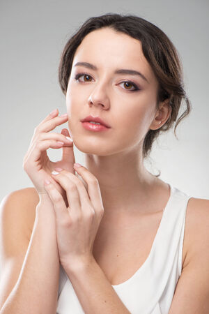 Beautiful woman holding her hands near face. Her skin is glowing. She looks natural and freshの写真素材