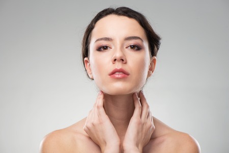 Beautiful woman holding her hands near face. Her skin is glowing. She looks natural and freshの写真素材