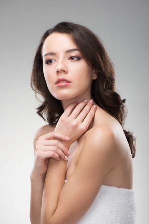 Beautiful woman holding her hands near neck. Her skin is glowing. She looks natural and fresh. She looks pensiveの写真素材