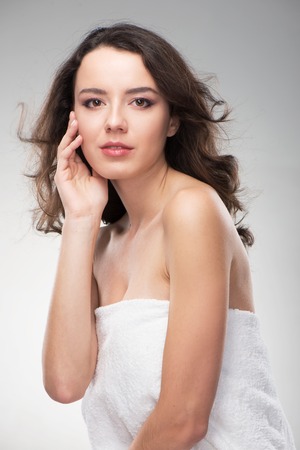 Beautiful woman holding her hands near face. Her skin is glowing. She looks natural and freshの写真素材