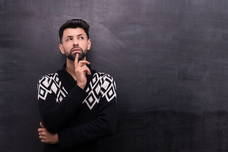 Photo of handsome young stylish man on blank chalkboard background. Man thoughtfully looking asideの写真素材