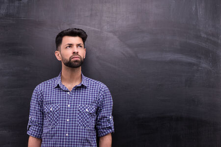 Photo of handsome young casual man on blank chalkboard background. Man looking asideの写真素材