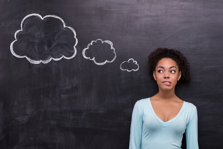 Photo of charming young afro-american woman on chalkboard background. Woman looking at cloud formed dialogの写真素材