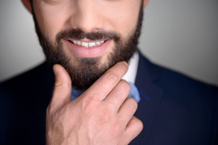 Close up photo of handsome stylish man with beard. Man wearing classic dark blue suit and a blue bow tie. Man smilingの写真素材