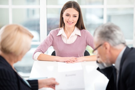 Young woman having an interview or business meeting with employers. Employers examining her CV. Office interior with big windowの写真素材