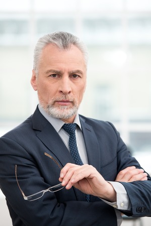 Businessman looking at camera. Office interior with big windowの写真素材