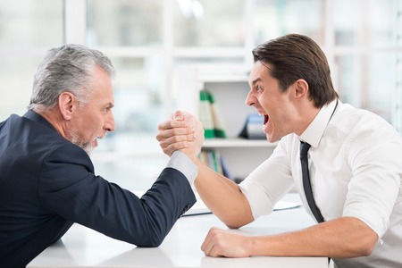 Two businessmen doing arm wrestling. Office interior with big windowの写真素材
