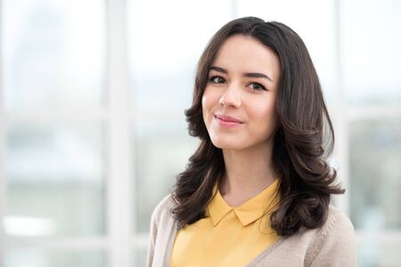 Portrait of young business lady looking at camera. Office interior with big windowの写真素材