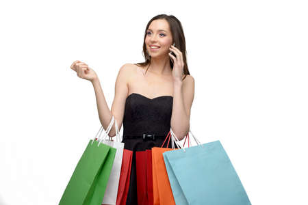 Caucasian beautiful young woman with colorful paper bags. She using phone. Concept for shop sales. Isolated on white backgroundの写真素材