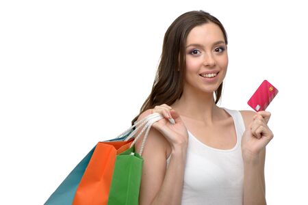 Caucasian young woman with colorful paper bags. She holding credit card and looking at camera. Concept for shop sales. Isolated on white backgroundの写真素材