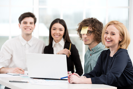 Funny photo of business team working with laptop. Office interior with window. Concept for teamworkの写真素材